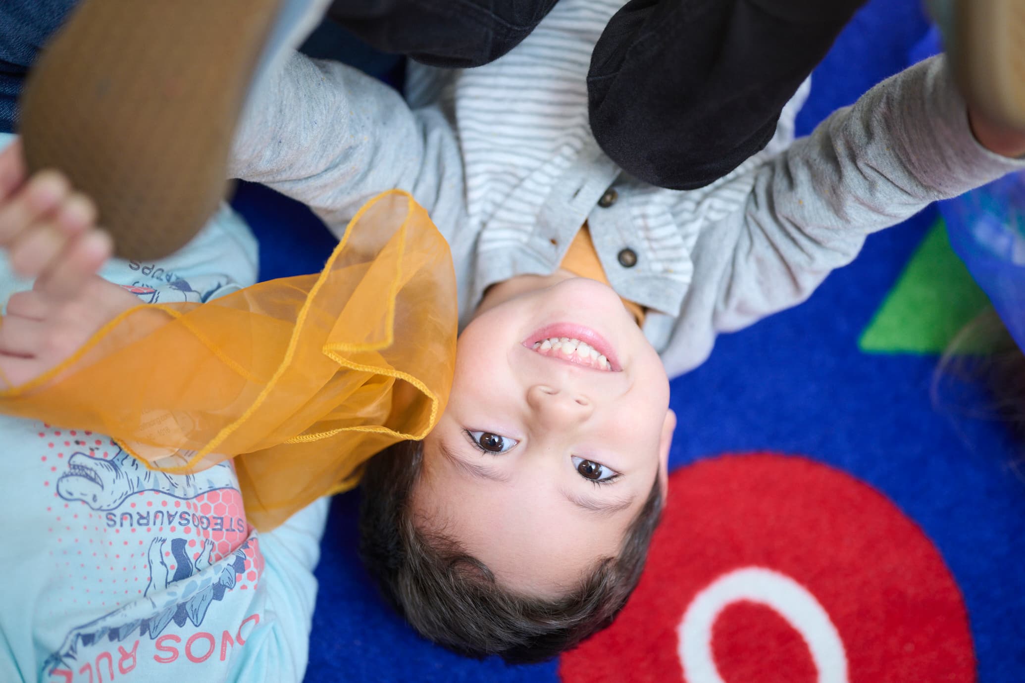 A young boy playing to the floor looking up at camera