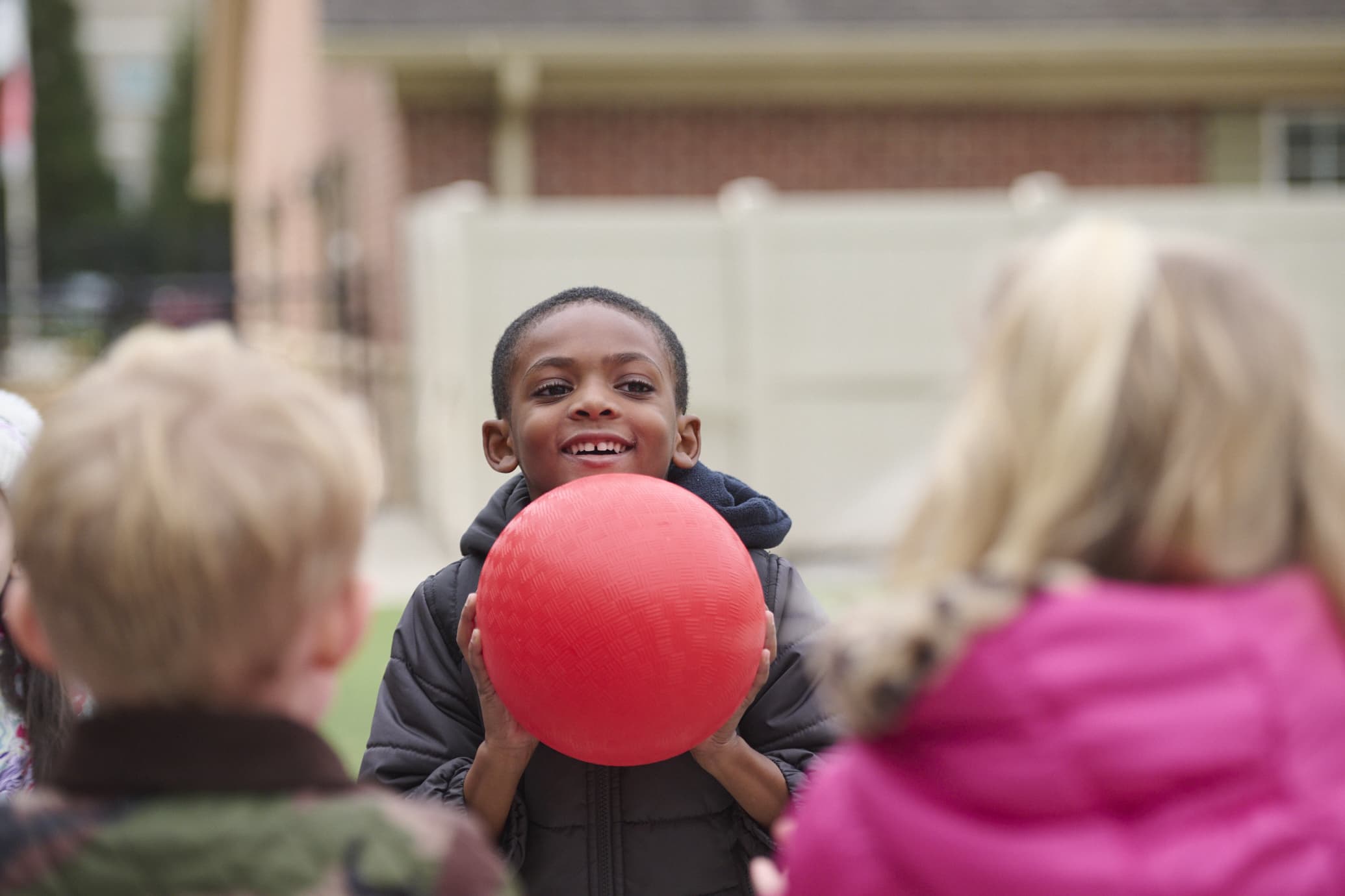 kindergarten child playing outside holding a ball